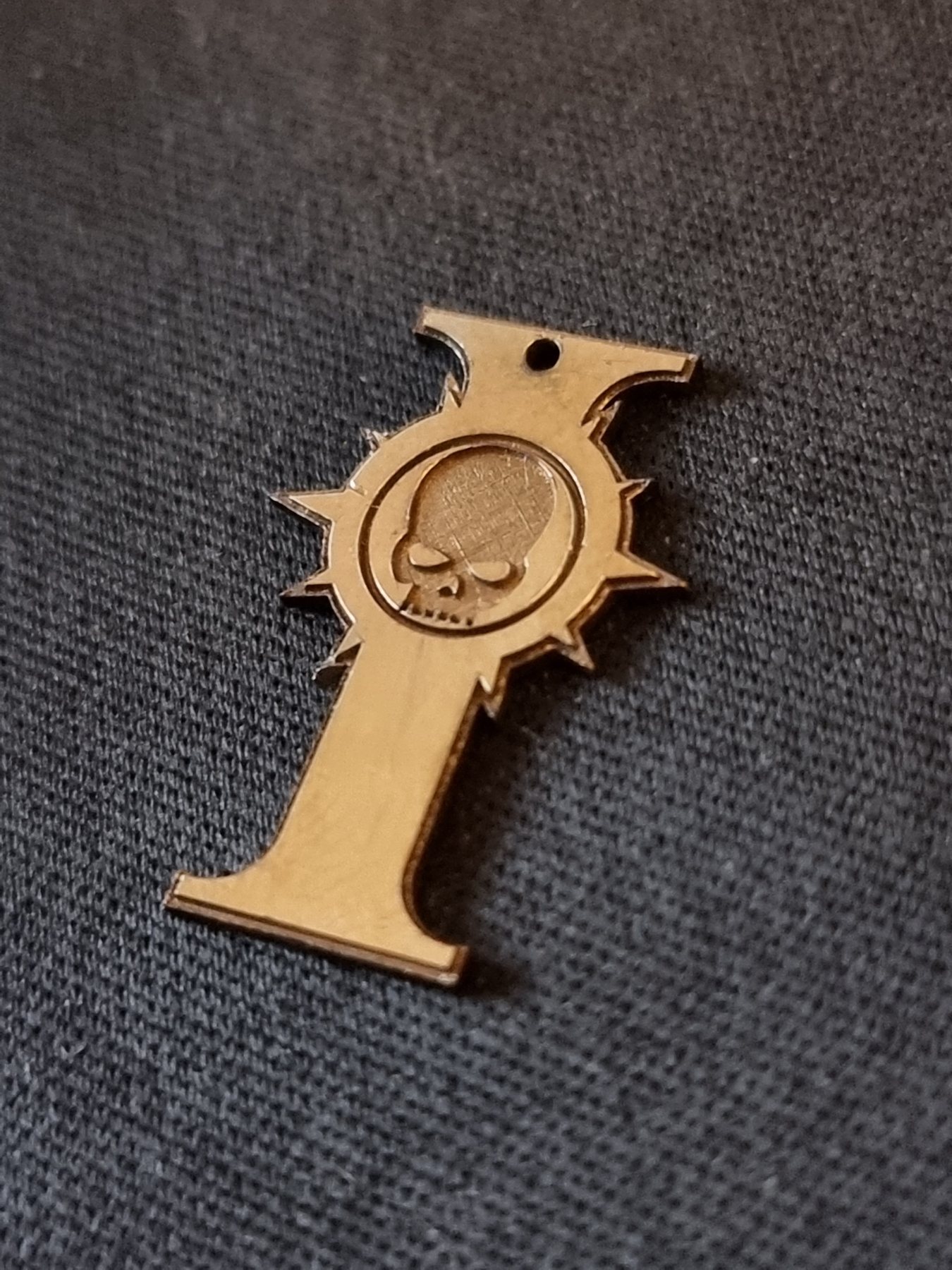 Three cut and engraved brass emblems on dark fabric