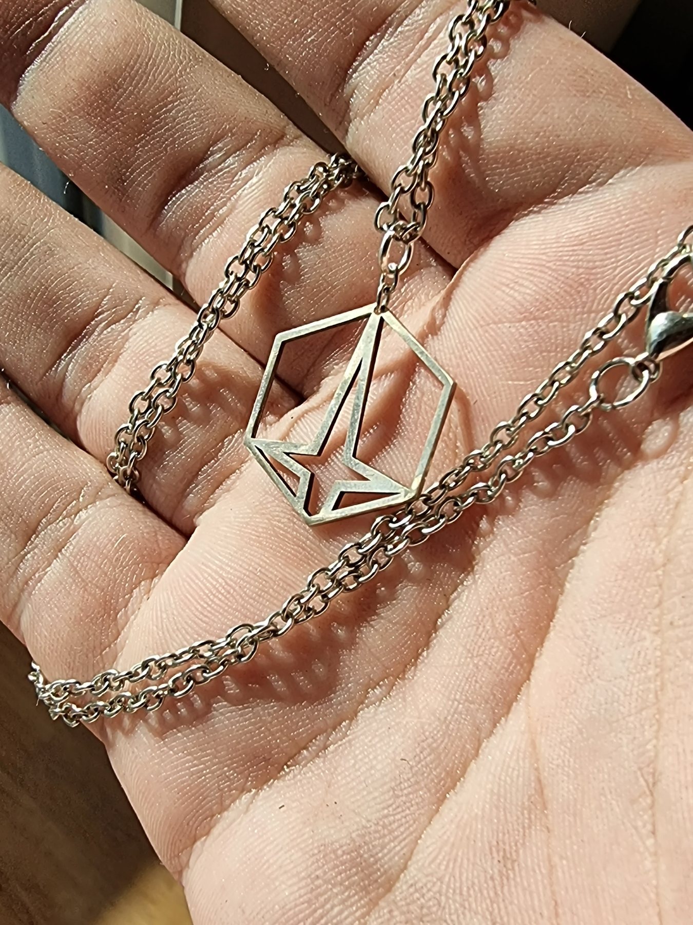 Custom engraved metal pendant held in a hand